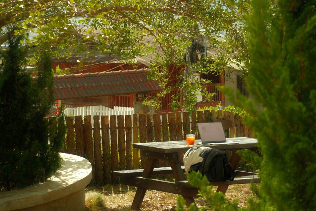A person with headphones working on a laptop at a wooden table in a modern cafe with a cup of coffee."
